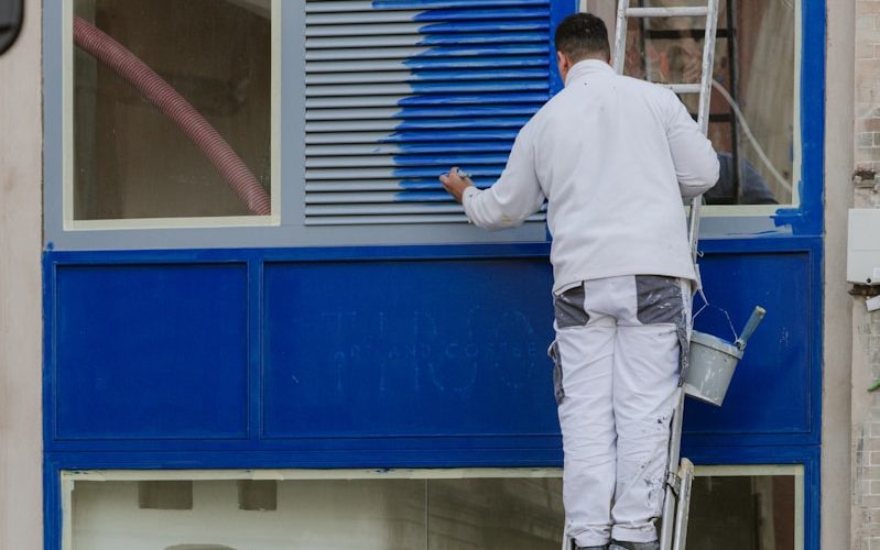 A man painting a window with a ladder